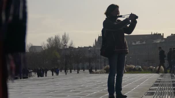 Бордо, Франция - CIRCA JANUARY 2016: People walking in the city. Женщина-туристка фотографирует на камеру, дождливый день в европейском городе, путешествует — стоковое видео