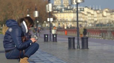 Bordeaux, Fransa - Ocak 2016 yaklaşık: Turist şehir. Şehir merkezinde adımlar üzerinde oturan ve cep telefonundan mesaj yazarak genç kız