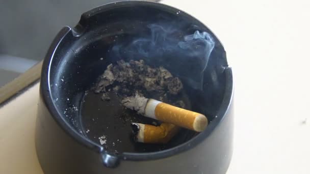 Harmful habit, smoldering cigarette butt lying in black ashtray, health problems — Stock Video