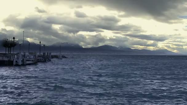 Olas salpicando en la superficie del agua agitada, nubes tormentosas, montañas en el horizonte — Vídeo de stock