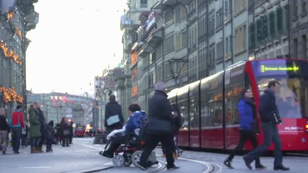 Bern, Svájc - körülbelül 2016. január: Az emberek a városban. Fogyatékkal élő személy modern tolószékben átkelés az utcán, toleráns társadalom egyenlő — Stock videók