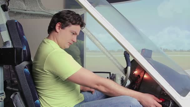 Excited young man sitting in flight simulator, turning controls on cockpit deck — Stock Video