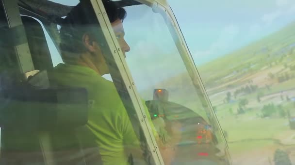 Jonge man kijkend naar groen landschap door vlucht simulator raam, luchtvaart — Stockvideo