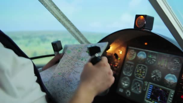 पुरुष पायलट स्टीयरिंग व्हील पकड़ रहा है, नक्शे पर उड़ान गंतव्य के लिए मार्ग की जांच कर रहा है — स्टॉक वीडियो