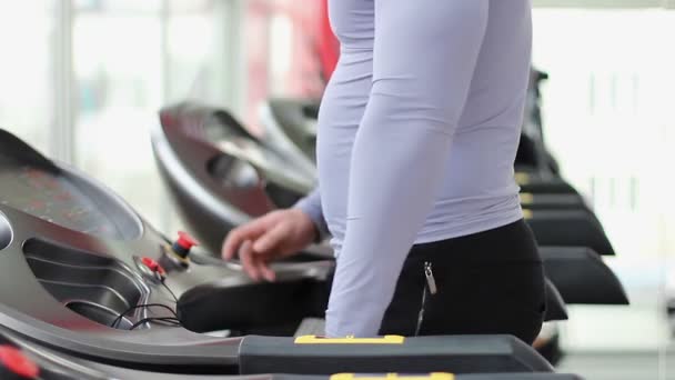 Sportive muž cvičení na běžeckém pásu, rozcvičení před aktivní trénink v tělocvičně — Stock video