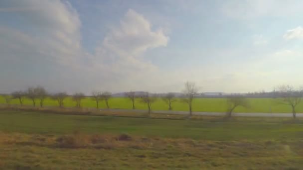 Vue du train se déplaçant à grande vitesse, passant devant les champs verts, les passages à niveau — Video