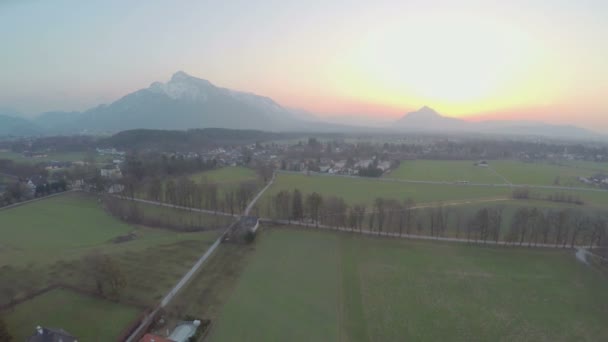 Lindas montanhas escondendo sol no horizonte, campos agrícolas verdes, incrível nascer do sol — Vídeo de Stock