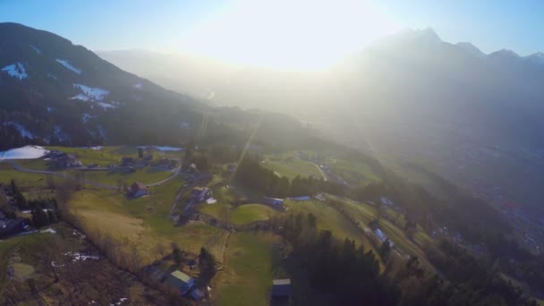 Luftaufnahme eines kleinen Bauerndorfes auf einem grünen Hügel des Berges im Sonnenuntergang — Stockvideo