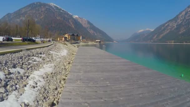 Повітряний знімок дерев'яної набережної озера, поверхня глибокої блакитної води, красиві гори — стокове відео