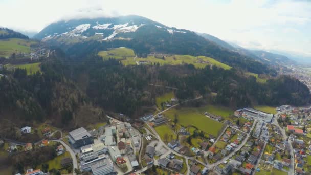 Повітряний постріл великого міста, красиві Альпи навколо нього, зелені спуск, засніжені вершини — стокове відео