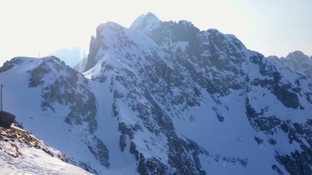 Verticale pan van besneeuwde bergen en felle zon in blauwe hemel. Winterlandschap — Stockvideo