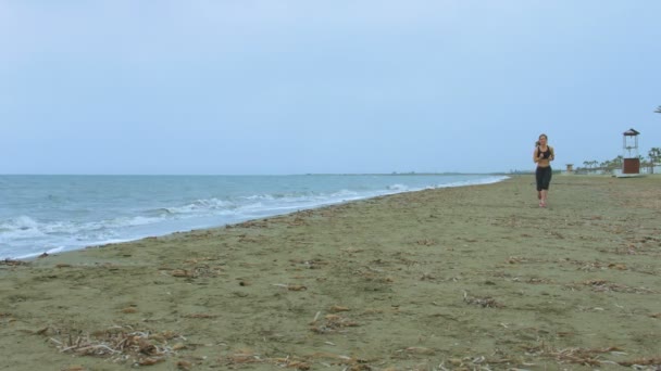 Jonge vrouw met fit lichaam jogging op zandstrand in de ochtend. Gezondheidszorg — Stockvideo