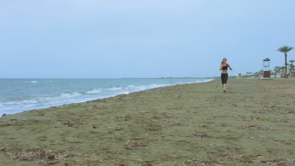 海辺で朝の体操、海岸に沿って実行している美しいスポーティな女性 — ストック動画