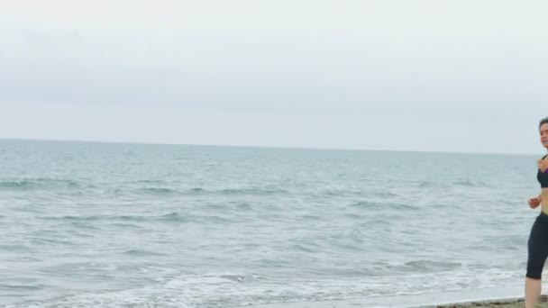 Jeune femme sérieuse avec une expression concentrée du visage courant le long de la plage de la mer — Video