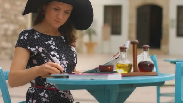 Young woman using old map to check route, putting marks, writing list of sights — Stock Video