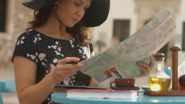 Mujer joven comprobando mapa, satisfecha con el plan de viaje, tomando notas con pluma — Vídeos de Stock