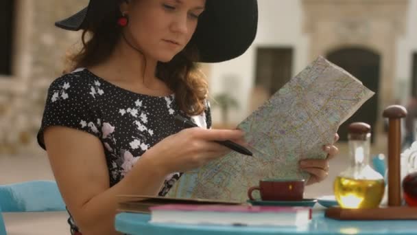 Elegante jonge vrouw in café planning tour in het buitenland, studeren kaart, controleren routes — Stockvideo