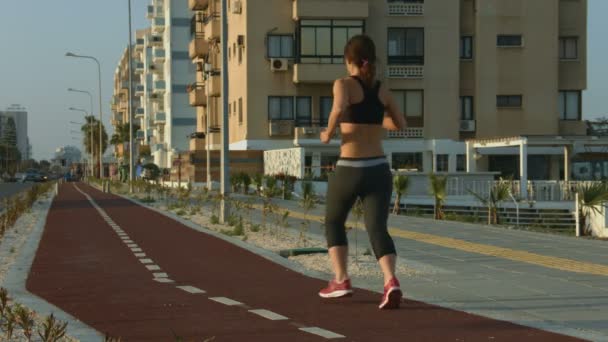 Giovane signora che corre lungo pista da jogging a piacimento. Forte motivazione al successo — Video Stock