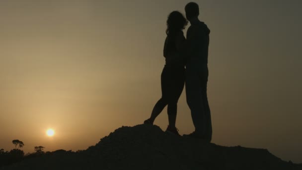 Menina feliz beijando namorado. Casal abraço, apreciando vista do pôr do sol incrível — Vídeo de Stock