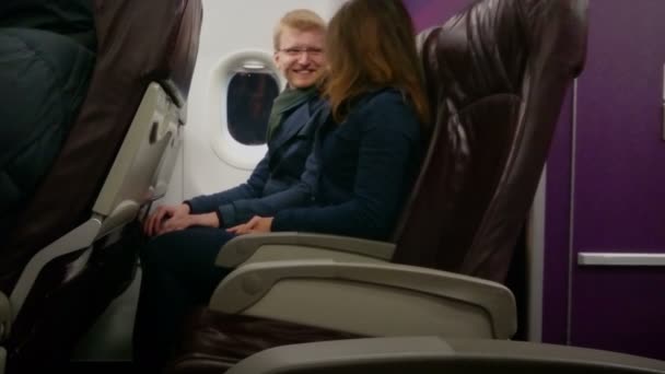 Pareja feliz viajando en avión de vacaciones, tomados de la mano, disfrutando del vuelo — Vídeos de Stock