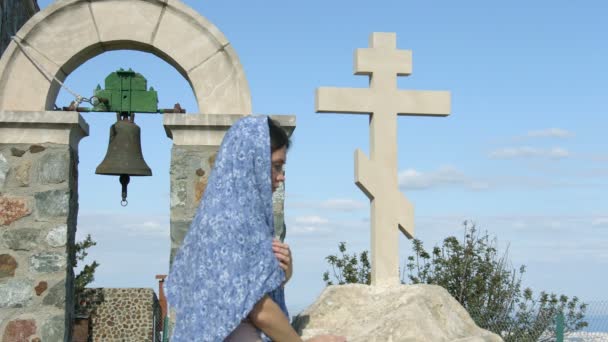 Joven feligrés rezando fuera de la iglesia, tocando la cruz de piedra — Vídeos de Stock