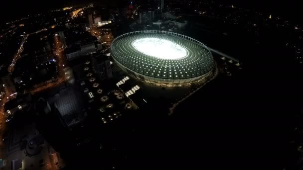 KYIV, UKRAINE - CIRCA JUNE 2016: Vista aérea do estádio Olimpiyskiy. Estádio de esportes brilhantemente iluminado durante o sobrevoo da cidade noturna, paisagem urbana incrível — Vídeo de Stock