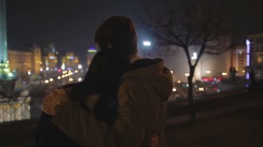 Sevgi ve bakım, gece şehir manzarayı çift kucaklama kız genç adam