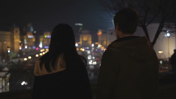 Couple of teenagers looking at night city lights, preparing to run away together — Stock Video