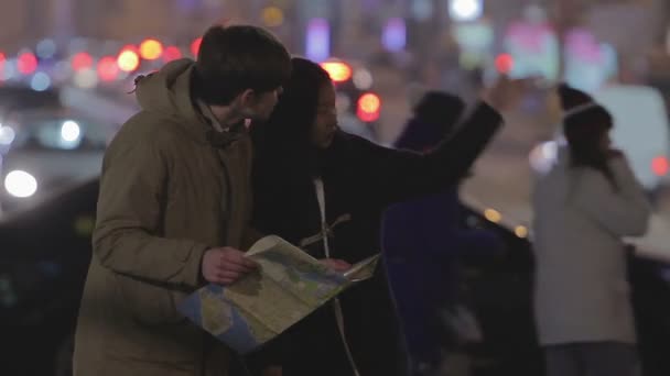 Young lady helping foreign guest to find way in big city, checking map together — Stock Video