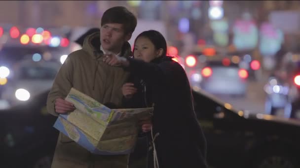 Young woman and man looking at map, searching for right way, lost in big city — Stock Video