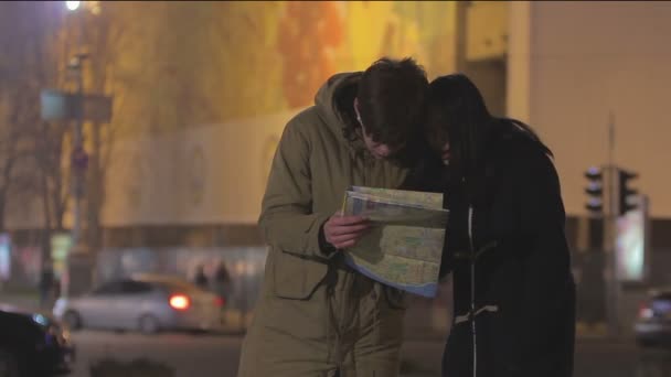 Jovens viajam para o exterior, perdidos em megalopolis, procurando diretamente no mapa da cidade — Vídeo de Stock