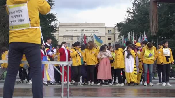 GINEBRA, SUIZA - CIRCA ENERO 2016: Estudiantes coreanos en gira por la paz en Europa. Jóvenes asiáticos en varios trajes posando para una foto de grupo cerca de la Oficina de la ONU en Ginebra — Vídeos de Stock
