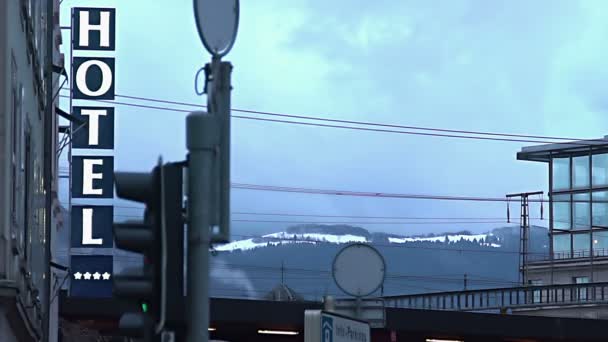 Вывеска отеля на городской улице, снежный горный хребет на горизонте, популярный горнолыжный курорт — стоковое видео