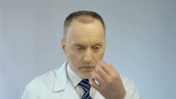 Перероблений головний лікар натирає очі, виглядаючи втомленим після напруженого робочого дня — стокове відео