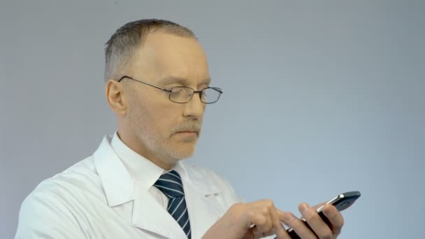 Лікар використовує мобільний телефон, набирає номер, телефонує пацієнту, щоб влаштувати зустріч — стокове відео