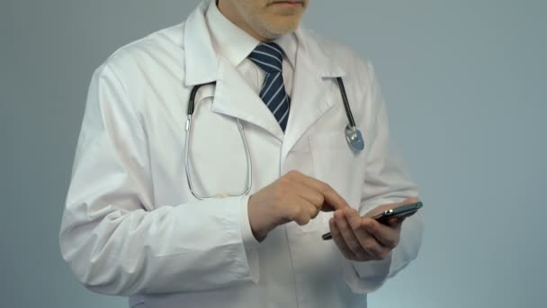 Лікар госпіталю набирає номер телефону на смартфон, телефонує до пацієнта — стокове відео