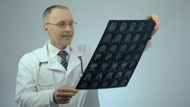 Счастливый улыбающийся доктор, проверяющий МРТ мозга, удовлетворенный результатами лечения — стоковое видео