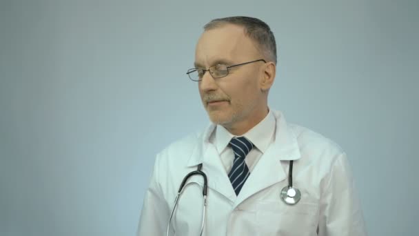 Счастливый улыбающийся врач-проктолог показывает резиновый шприц и смотрит в камеру — стоковое видео