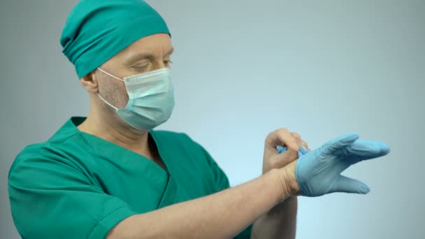 Nervous surgeon putting on medical gloves, preparing for serious operation — Stock Video