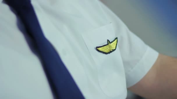 Professional pilot dressed in beautiful uniform sitting in cockpit, fixing tie — Stock Video