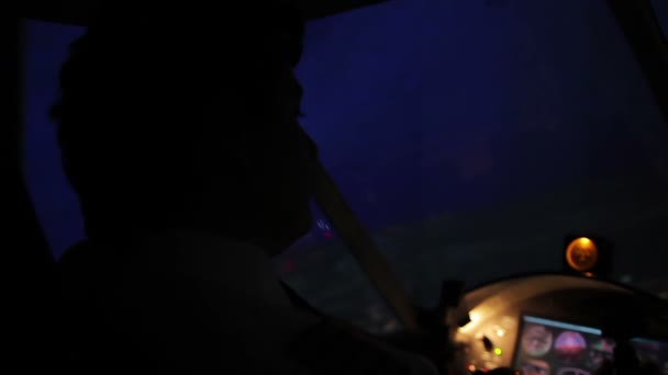 Pilot's silhouette navigating airplane and looking on beautiful night city — Stock Video