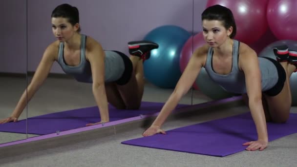 Mujer joven exitosa haciendo flexiones en el gimnasio, haciendo pulgares hacia arriba, sonrisa en la cara — Vídeos de Stock