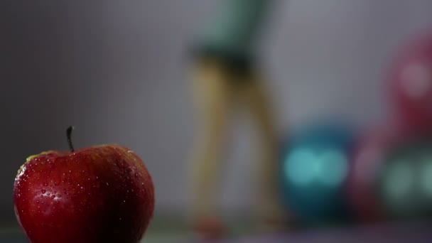 Primer plano de manzana fresca, mujer desenfocada haciendo sentadillas en el gimnasio, dieta de pérdida de peso — Vídeo de stock