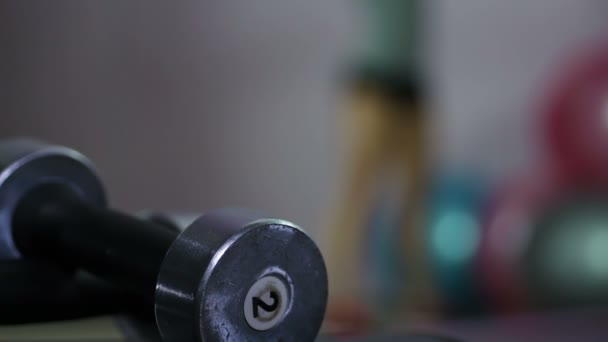 Kobieta w kucki w siłowni, rozmytym sylwetka, zbliżenie hantle do ćwiczeń — Wideo stockowe