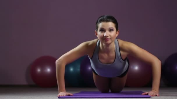 Mujer bonita activa haciendo flexiones de rodilla fácilmente con sonrisa en la cara, entrenamiento de gimnasio — Vídeo de stock