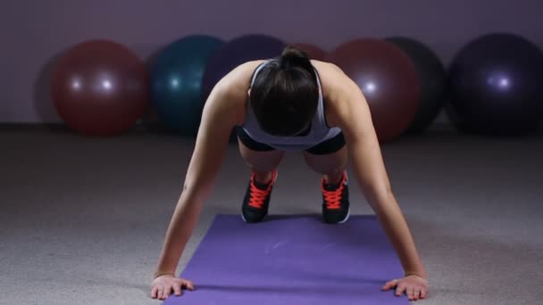 Femme sportive active faisant de l'exercice push-up, s'entraînant au gymnase, regardant la caméra — Video