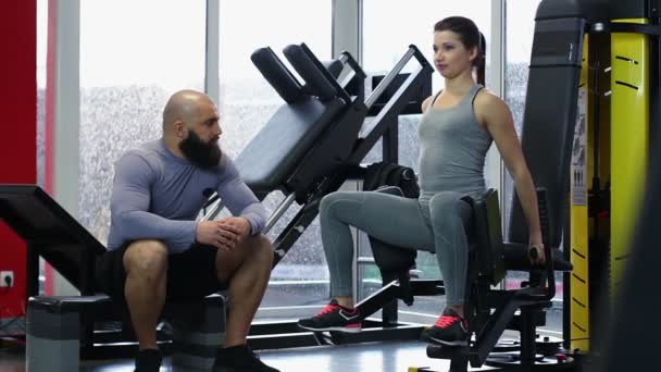 Pareja de jóvenes activos hablando durante el entrenamiento en el gimnasio, estilo de vida saludable — Vídeos de Stock