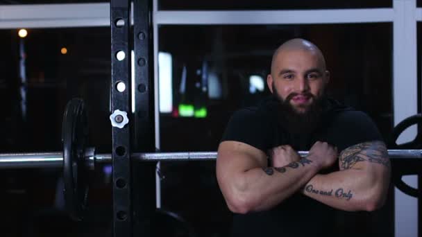 Starka muskulösa bodybuilder vilar på skivstång i gymmet med glada leende på ansiktet — Stockvideo