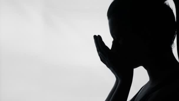 Депрессивная молодая женщина плачет, закрывая грустное лицо руками, женский силуэт — стоковое видео