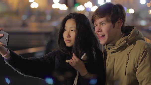 Pasangan remaja menarik wajah-wajah bodoh dan mengambil selfie di telepon, bersenang-senang — Stok Video